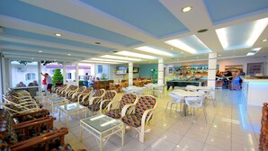 Un grand espace intérieur aménagé avec des rangées de chaises et de tables en osier, un coin bar et un écran de télévision.