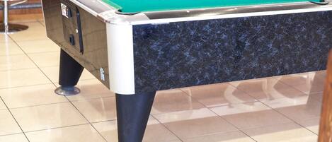 A pool table with a green felt surface, black marble sides, and metal legs.