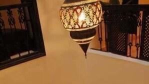 Une cour intérieure dotée d’une fontaine centrale, d’arcades et d’une lampe décorative.
