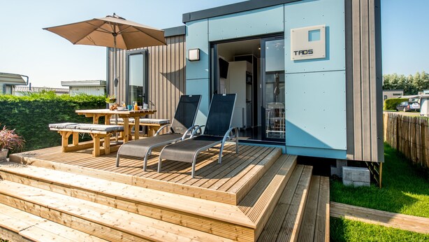 A modern outdoor deck with lounge chairs, a table, and an umbrella. - Holiday Village Knokke (Knokke-Heist)