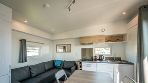 A compact living space with a sofa, a dining table, a kitchen area, and a window. - Holiday Village Knokke (Knokke-Heist)