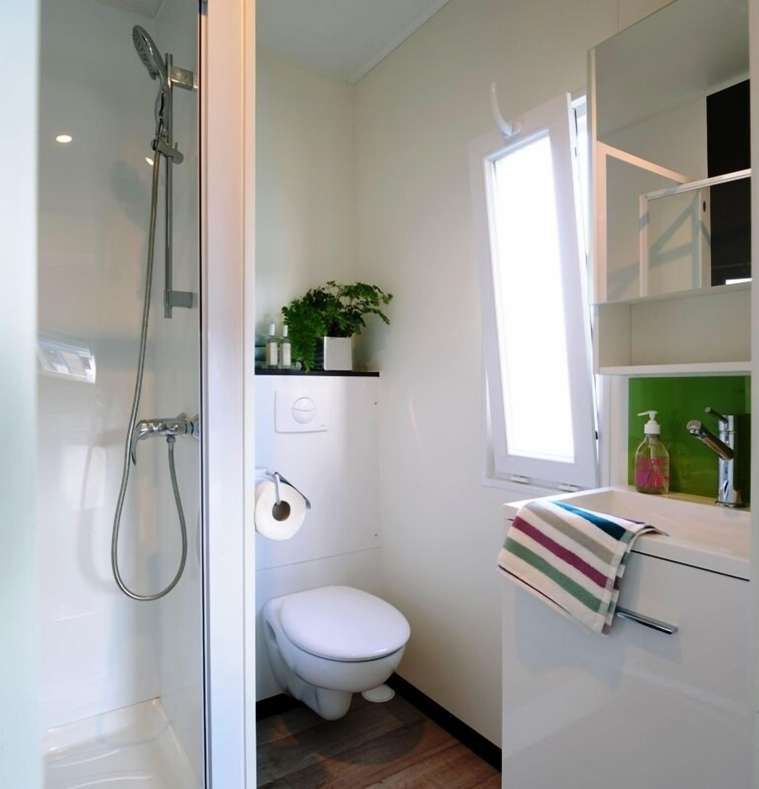 Un baño pequeño con ducha, inodoro y lavamanos.