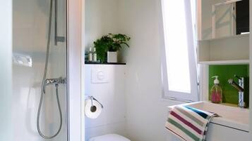 Un baño pequeño con ducha, inodoro y lavamanos.