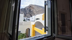 A window view of a building with a mountain in the background.