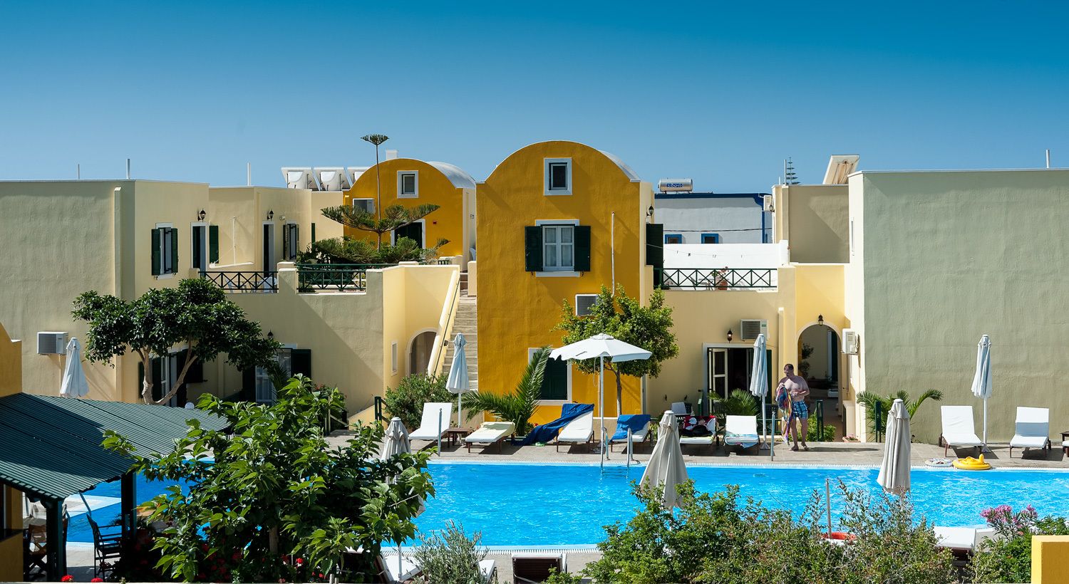 A poolside area with lounge chairs, umbrellas, and a clear blue pool.