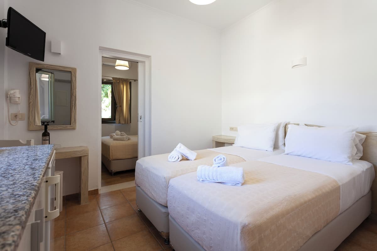 A hotel room with two beds, a bathroom, a TV, and a minibar.