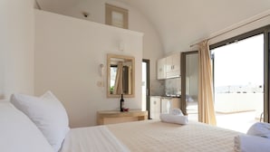 A hotel room with a large bed, a desk with a mirror, a minibar, and a view of the outside.