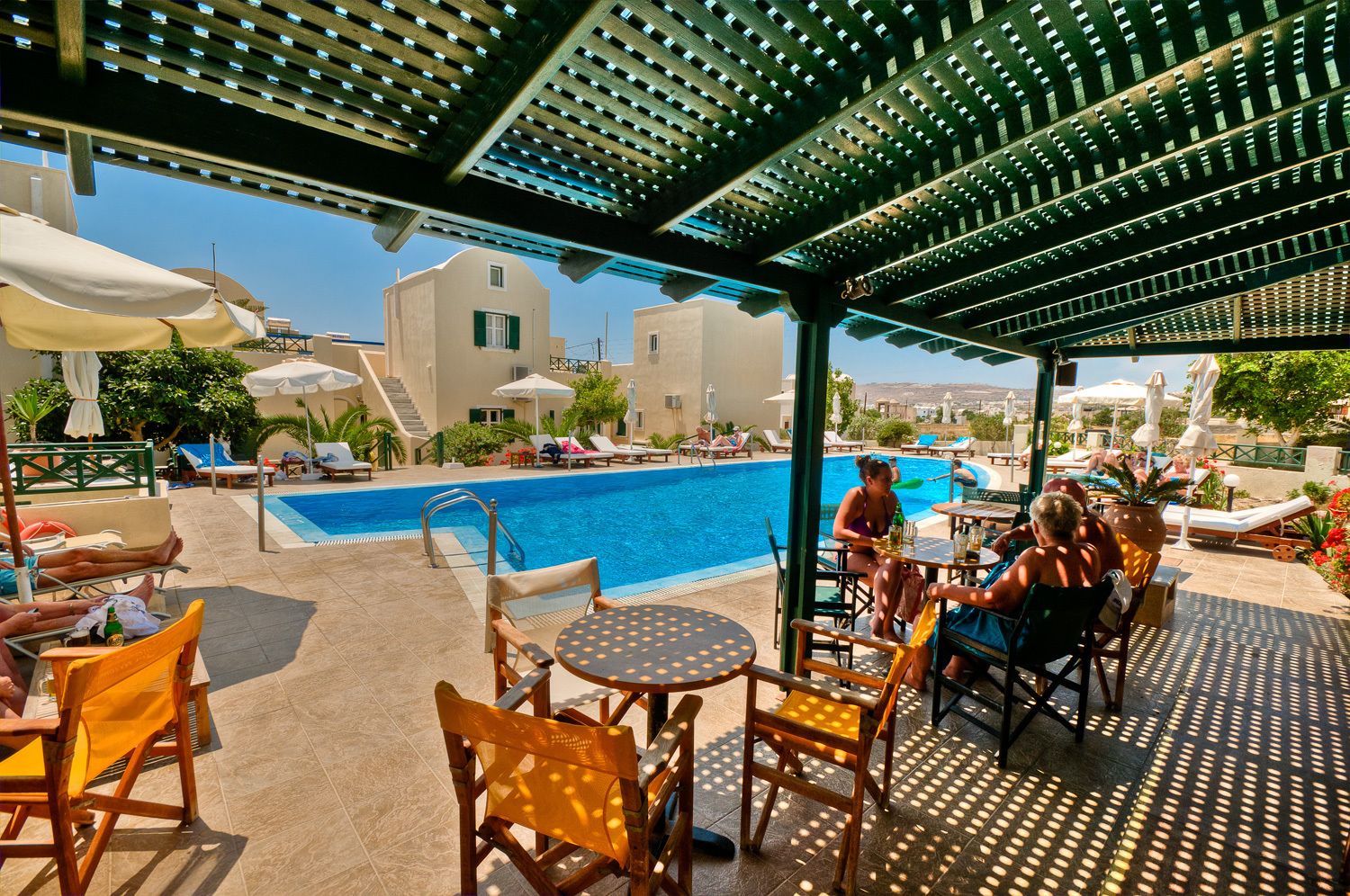 A poolside area with lounge chairs, tables, and umbrellas.