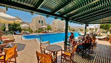 A poolside area with lounge chairs, tables, and umbrellas.