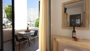 A balcony with a table, chairs, and a bowl of fruit.