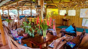 A wooden interior with rustic furniture, a central table, and a bamboo wall.