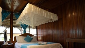 A wooden room with a bed, a nightstand, a table, and a canopy bed.