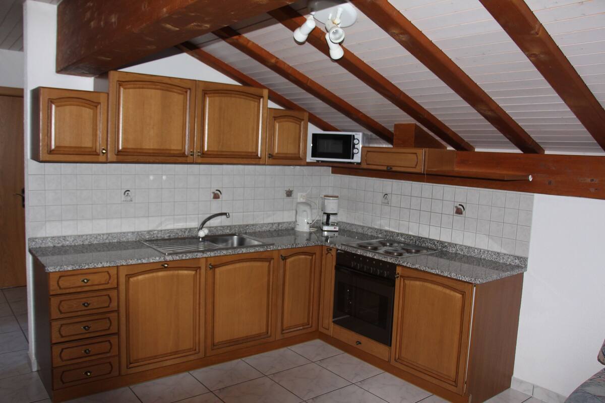 Una cocina con armarios de madera, microondas, fregadero y lavavajillas.