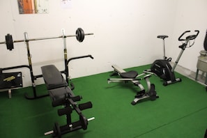 A gym with a bench press, a squat rack, and an elliptical machine.