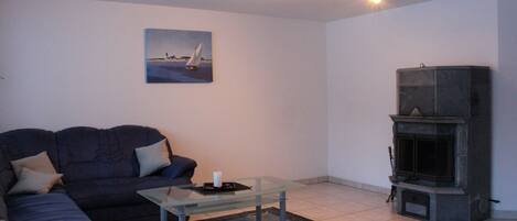 A living room with a sofa, a glass coffee table, a fireplace, and a painting on the wall.