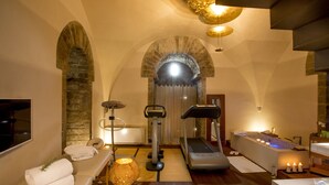 A spa room with a massage table, exercise equipment, a bathtub, and a large window. - Torre Mannelli Suites (Florence)