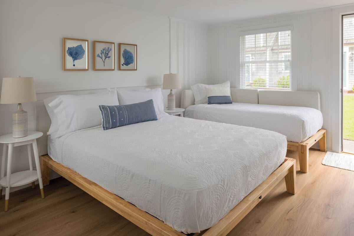 A bedroom with a large bed, two bedside tables, and a window with blinds.