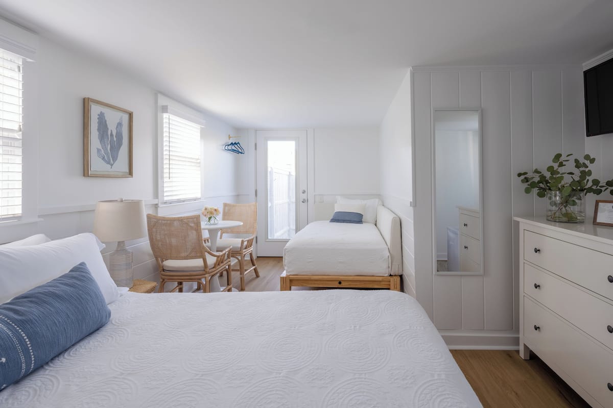 A bedroom with a large bed, a bedside table, a chair, a desk, and a dresser.