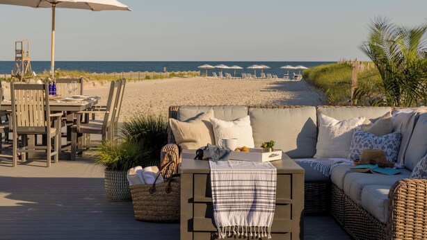 A beachside seating area with a sofa, chairs, and umbrellas. - Inn on the Beach  (Harwich Port)