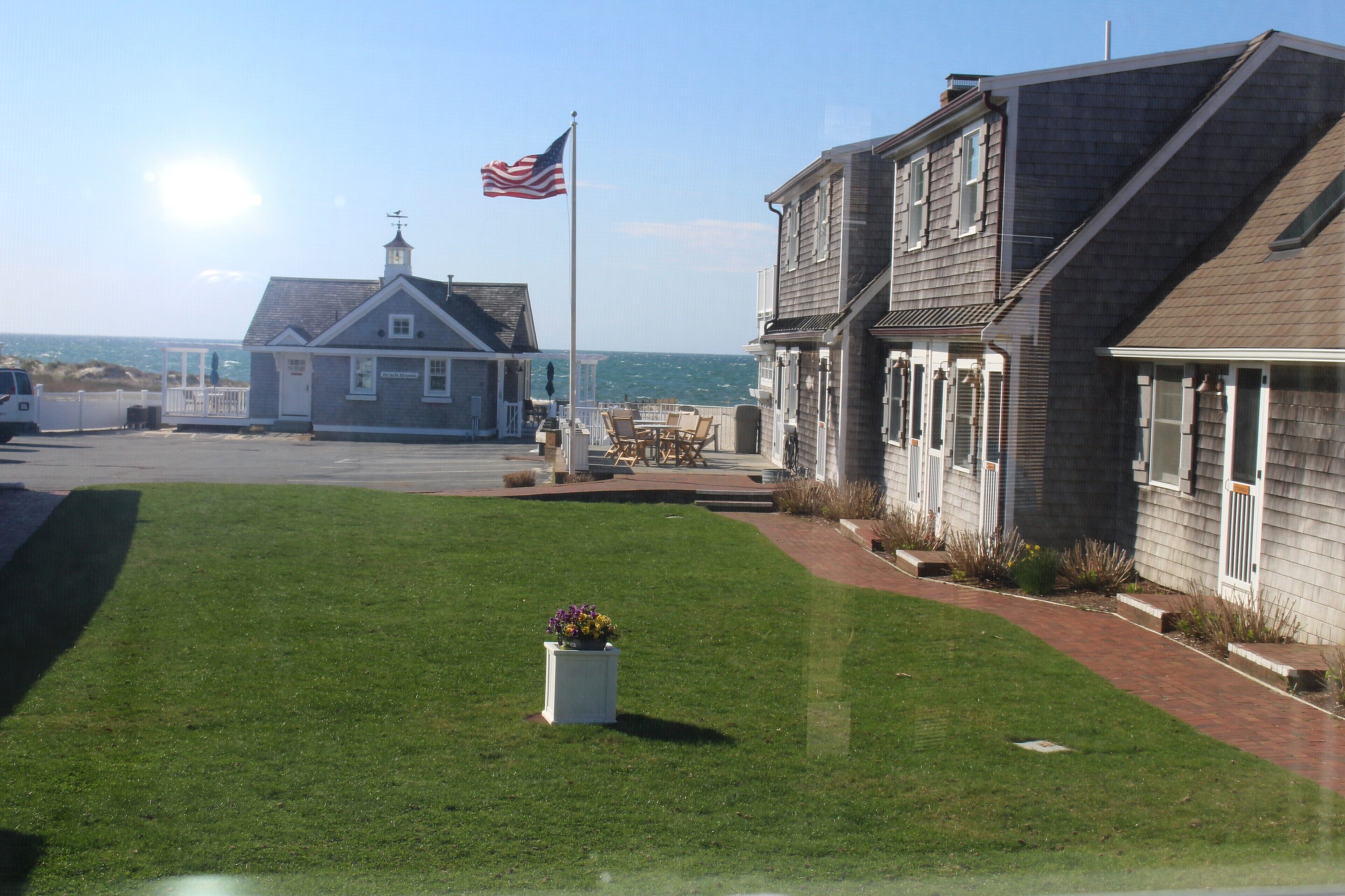 A coastal building with a flag, a grassy lawn, and a view of the sea.