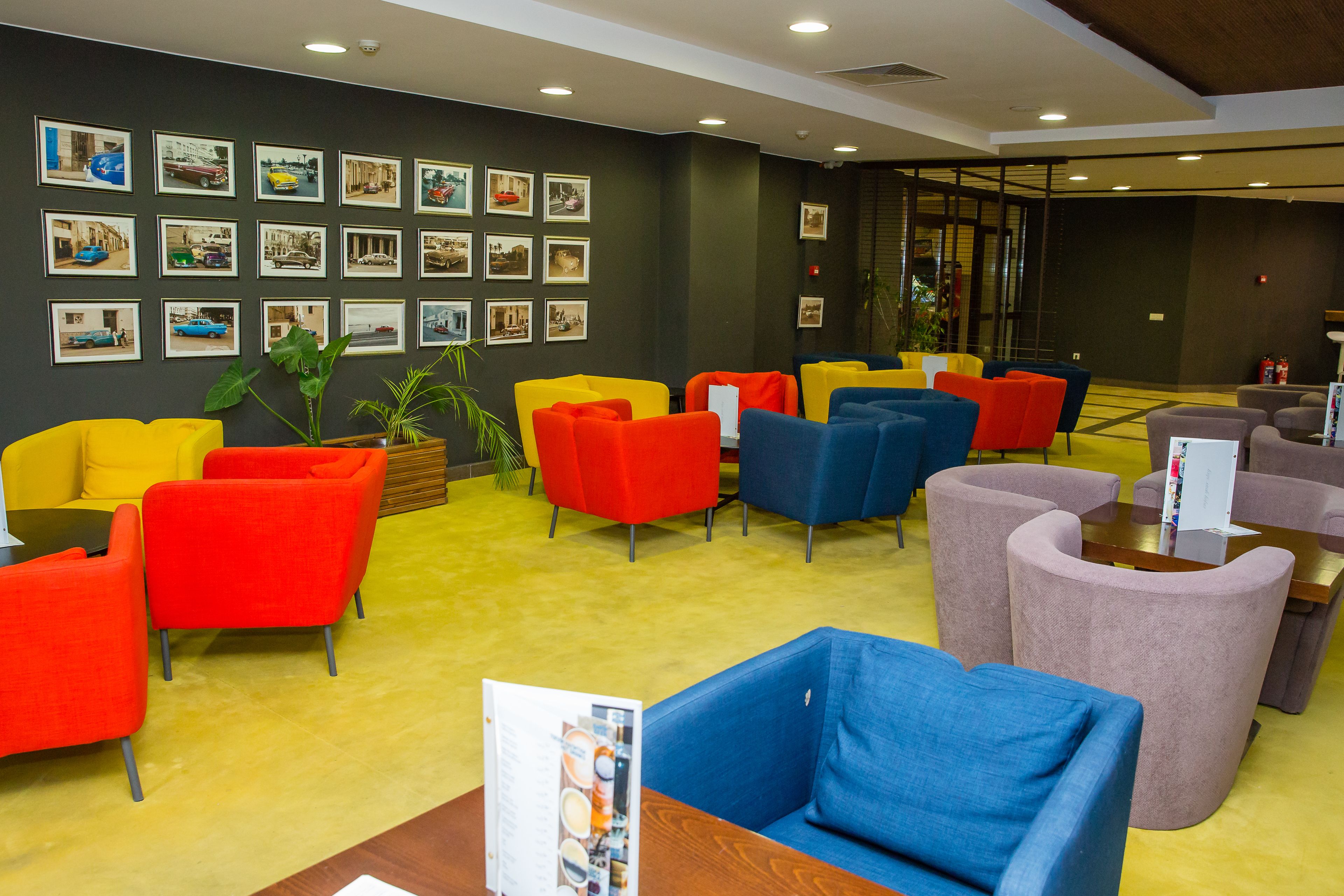 A lobby with colorful seating, a wall of framed pictures, and a reception desk.