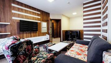 Una sala de estar moderna con un sofá, sillones, una mesa de centro y un televisor de pantalla plana montado en la pared.