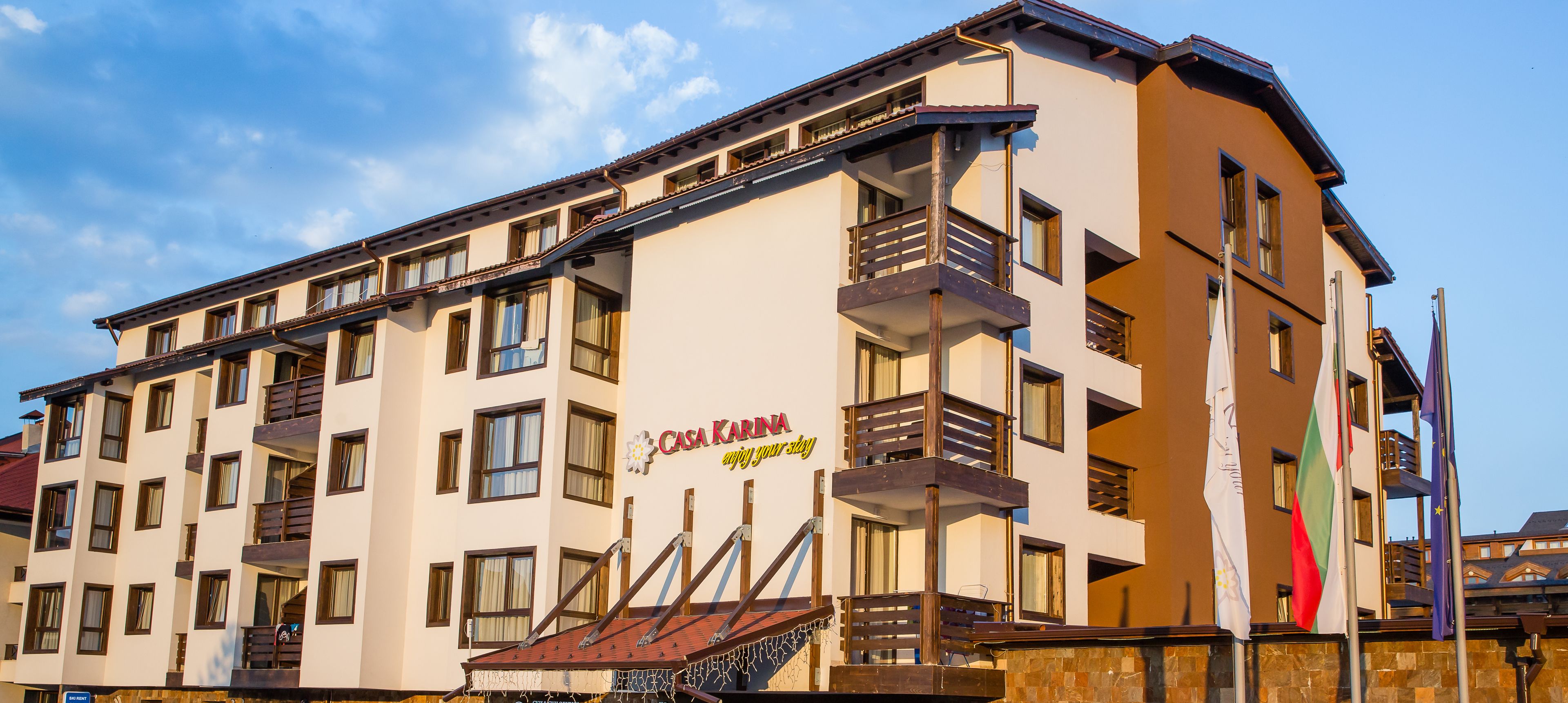 A multi-story hotel with balconies, a sign reading "Casa Karin," and flags on the right side.