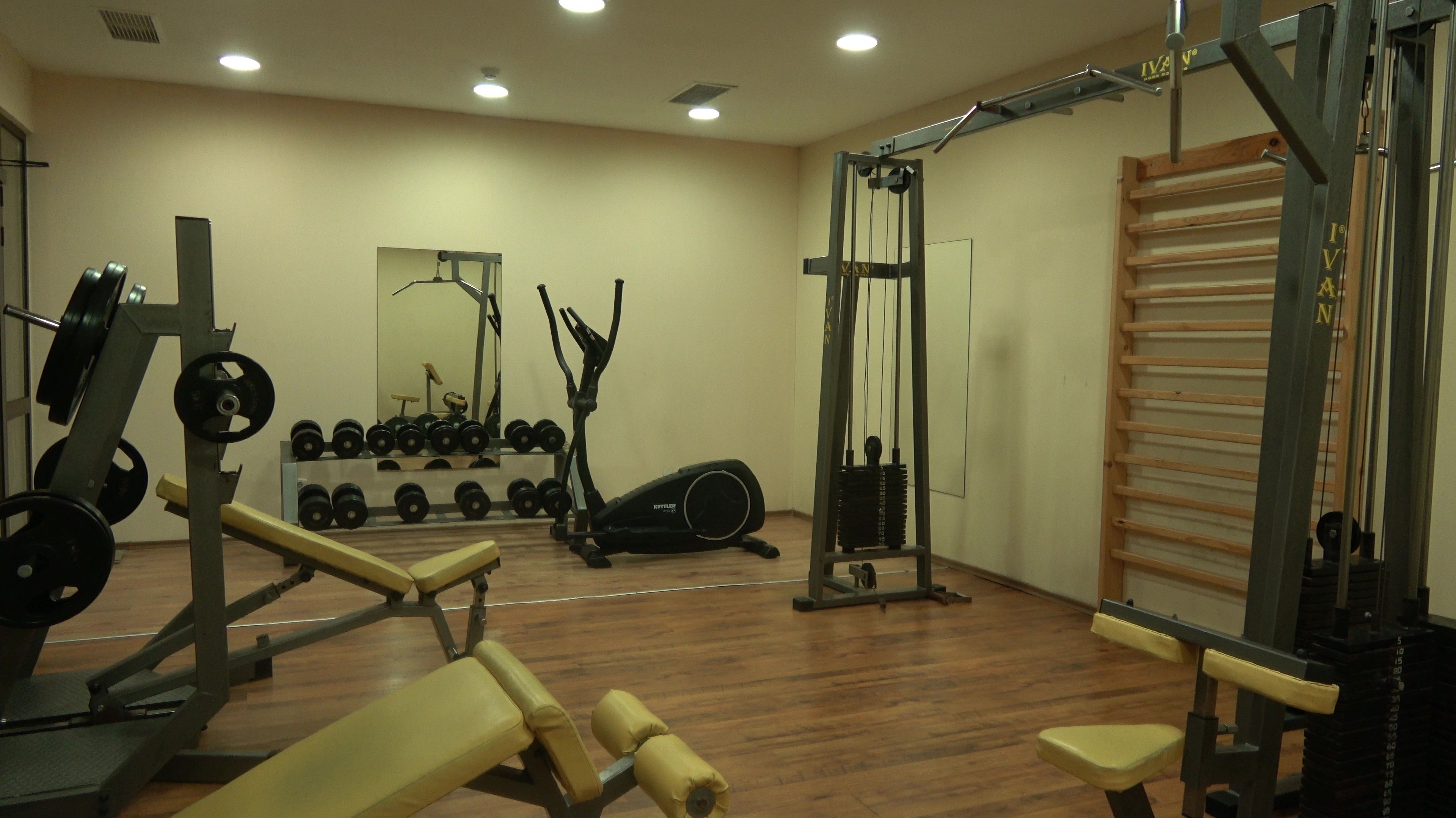 A gym with weightlifting equipment, cardio machines, and a mirror.
