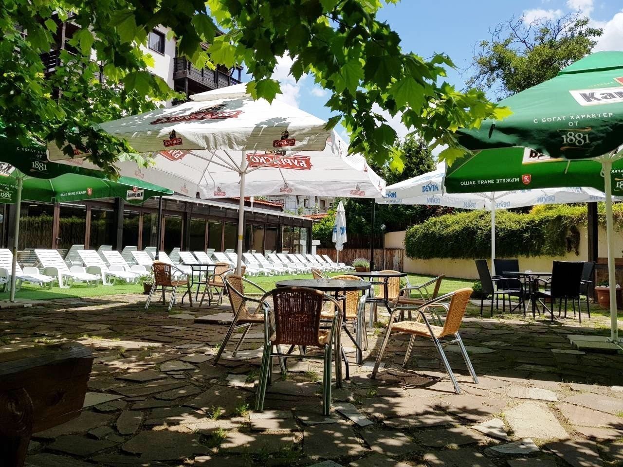 An outdoor seating area with tables and chairs, umbrellas, and a building in the background.