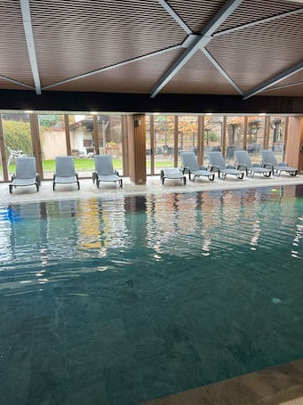 Una piscina techada, sillones reclinables de piscina