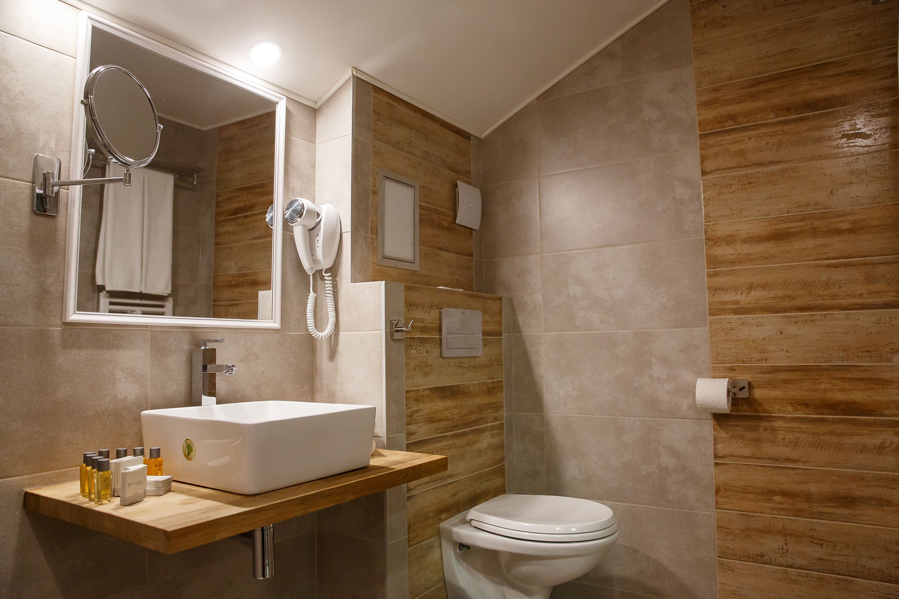 Une salle de bain moderne avec un meuble-lavabo en bois, un grand miroir, un lavabo blanc et des toilettes.