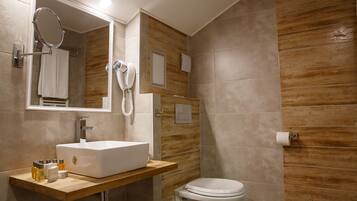 A modern bathroom with a wooden vanity, a large mirror, a white sink, and a toilet.