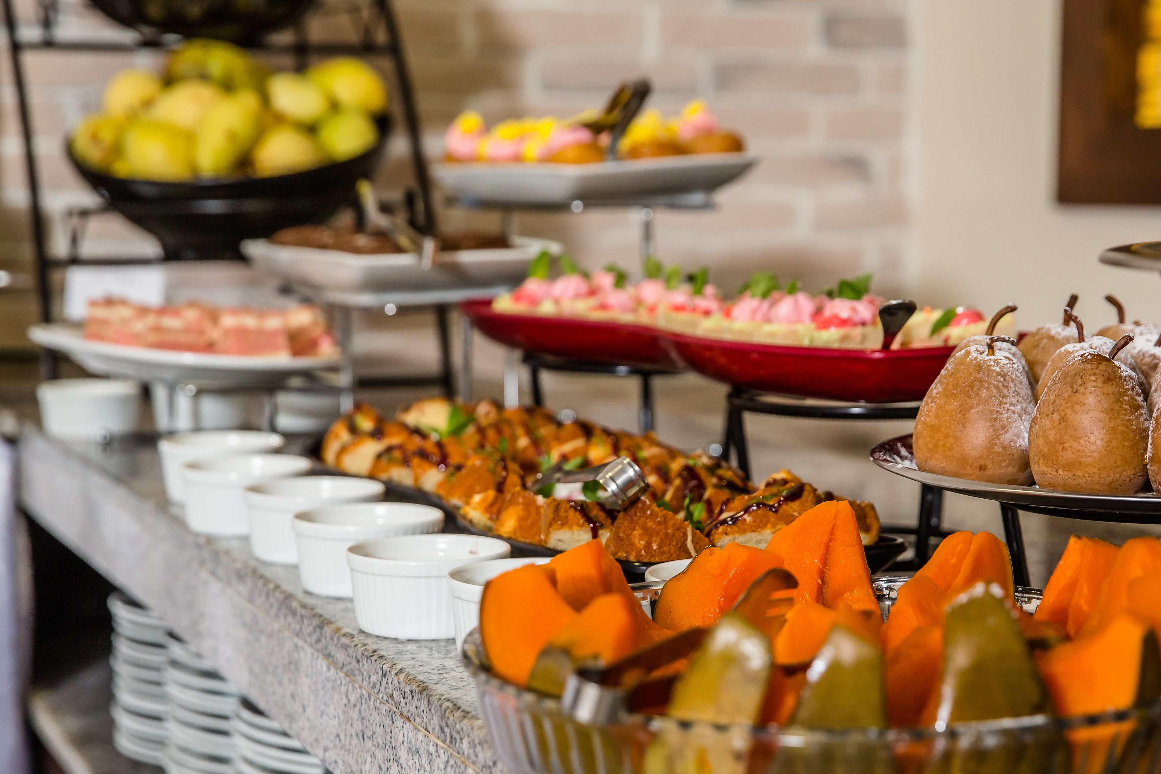 Un buffet con diverse pietanze, tra cui frutta, pasticcini e verdure.