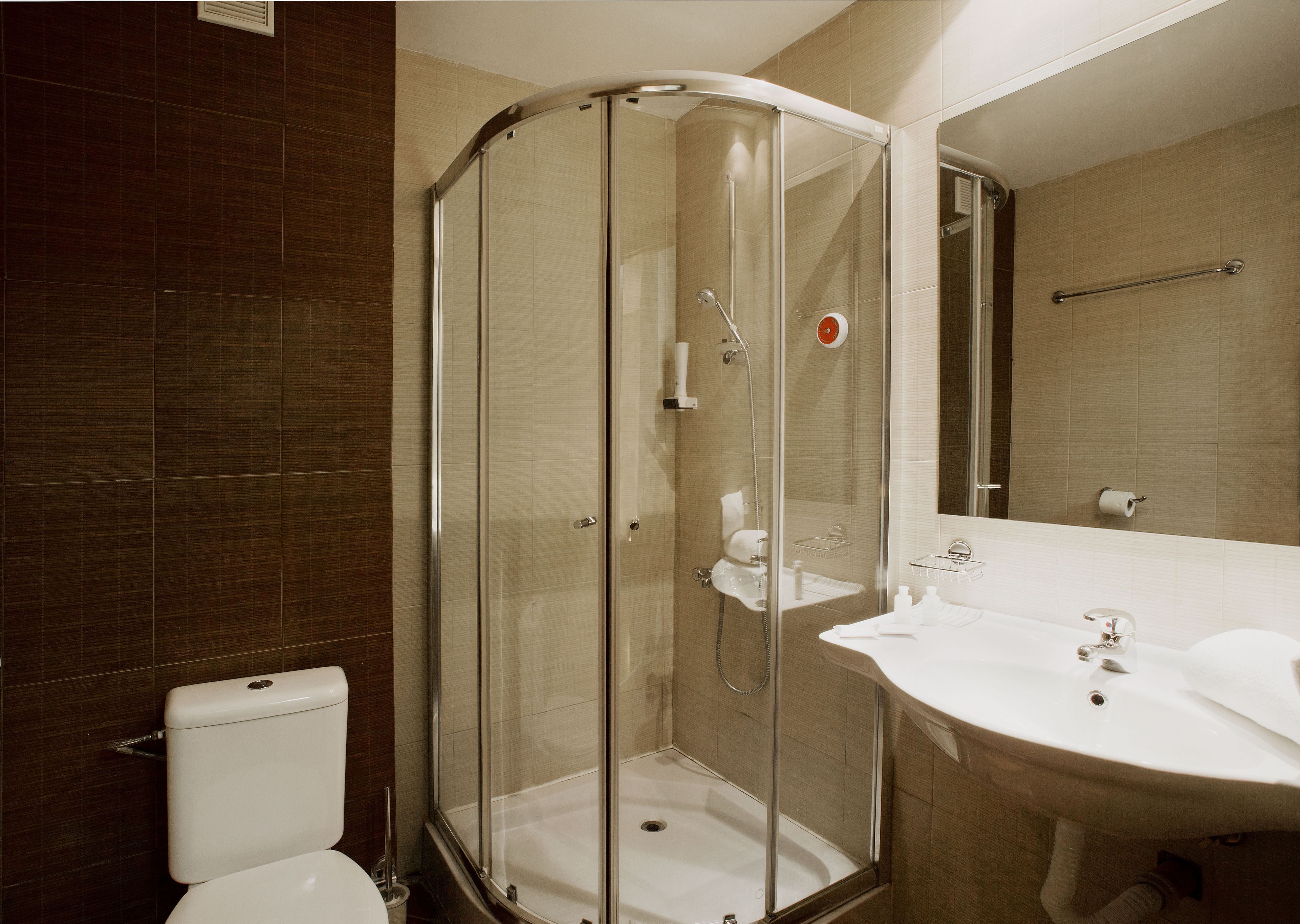 Ein modernes Badezimmer mit einer Duschkabine, einem weißen Waschbecken und einer Toilette.
