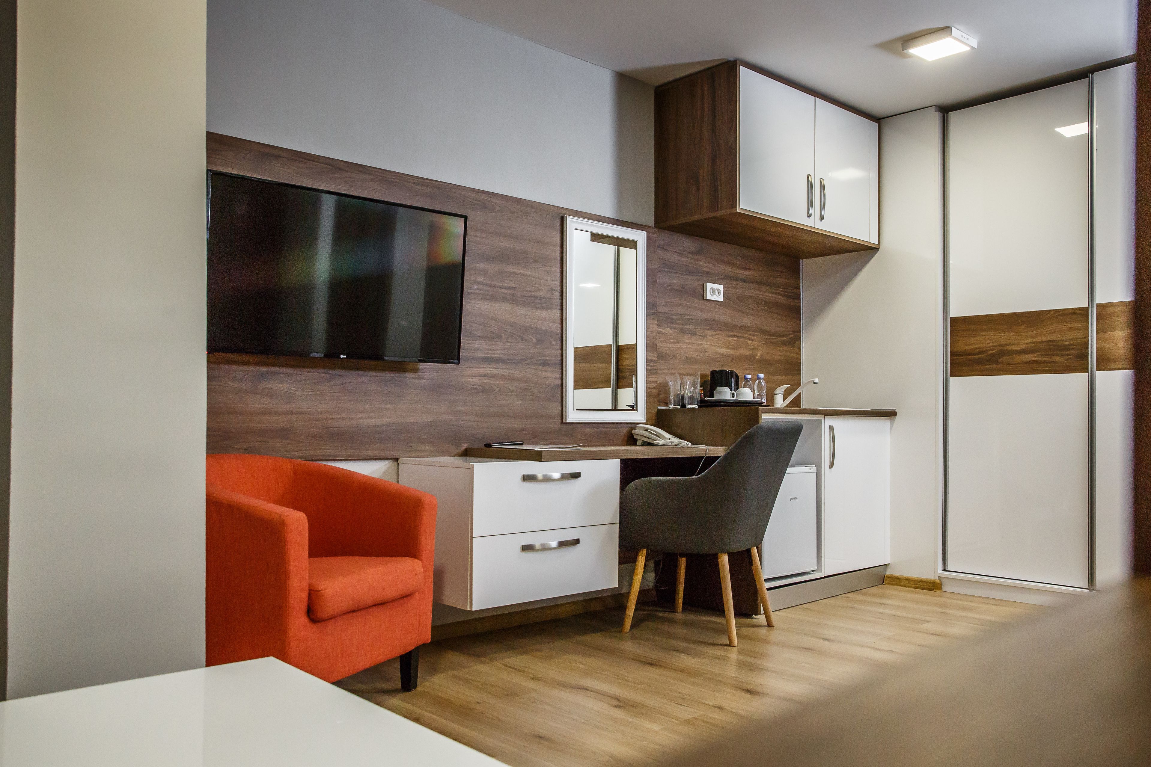 A compact kitchen with a dining area, a flat-screen TV, and a cabinet with a mirror.