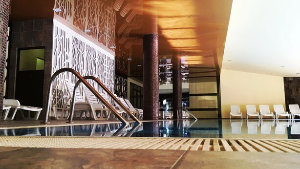 Un área de piscina con sillones reclinables y una pared decorativa.
