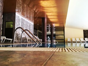 A pool area with lounge chairs and a decorative wall. - Casa Karina Hotel (Bansko)
