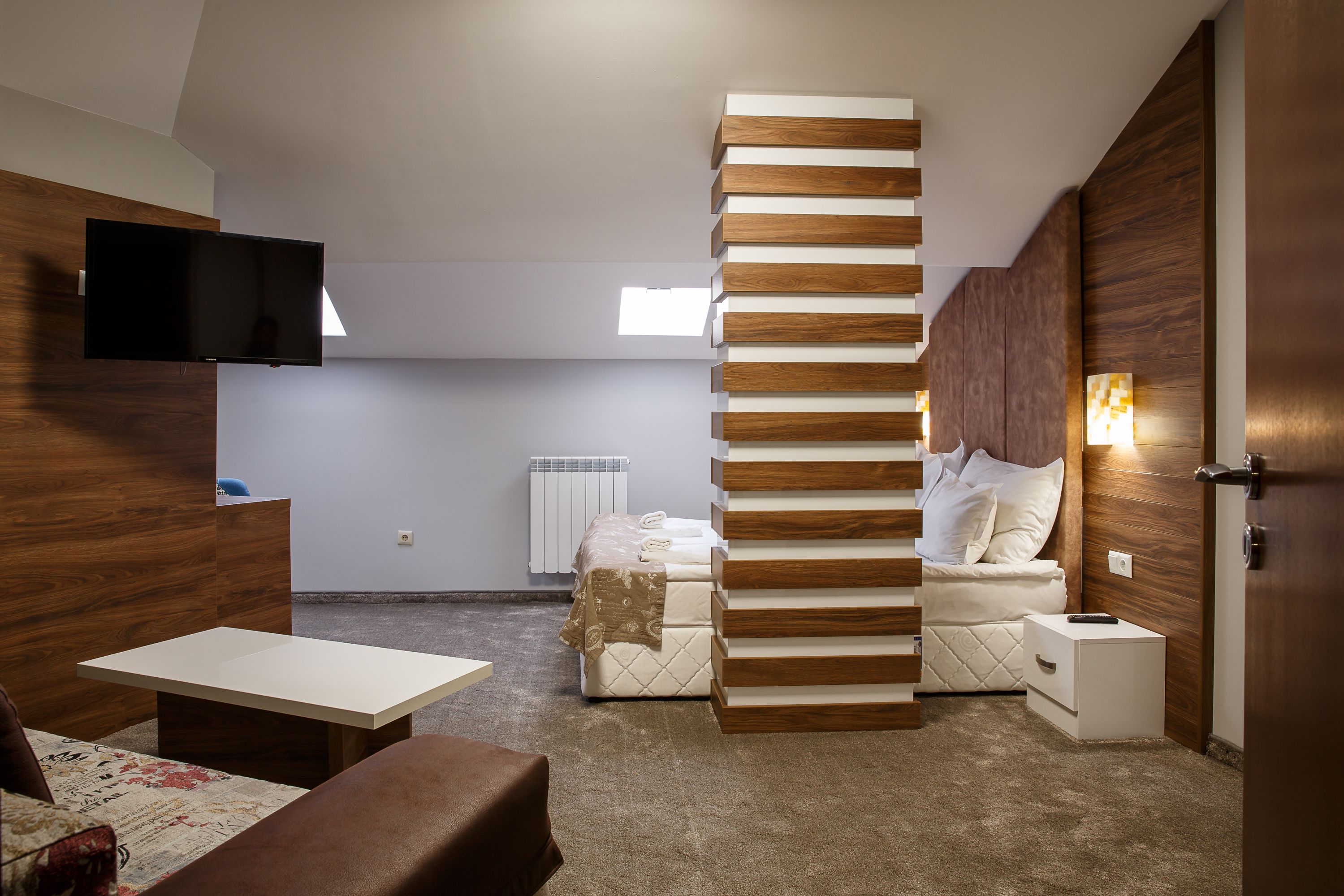 A modern bedroom with a bed, a TV, a desk, and a sofa.