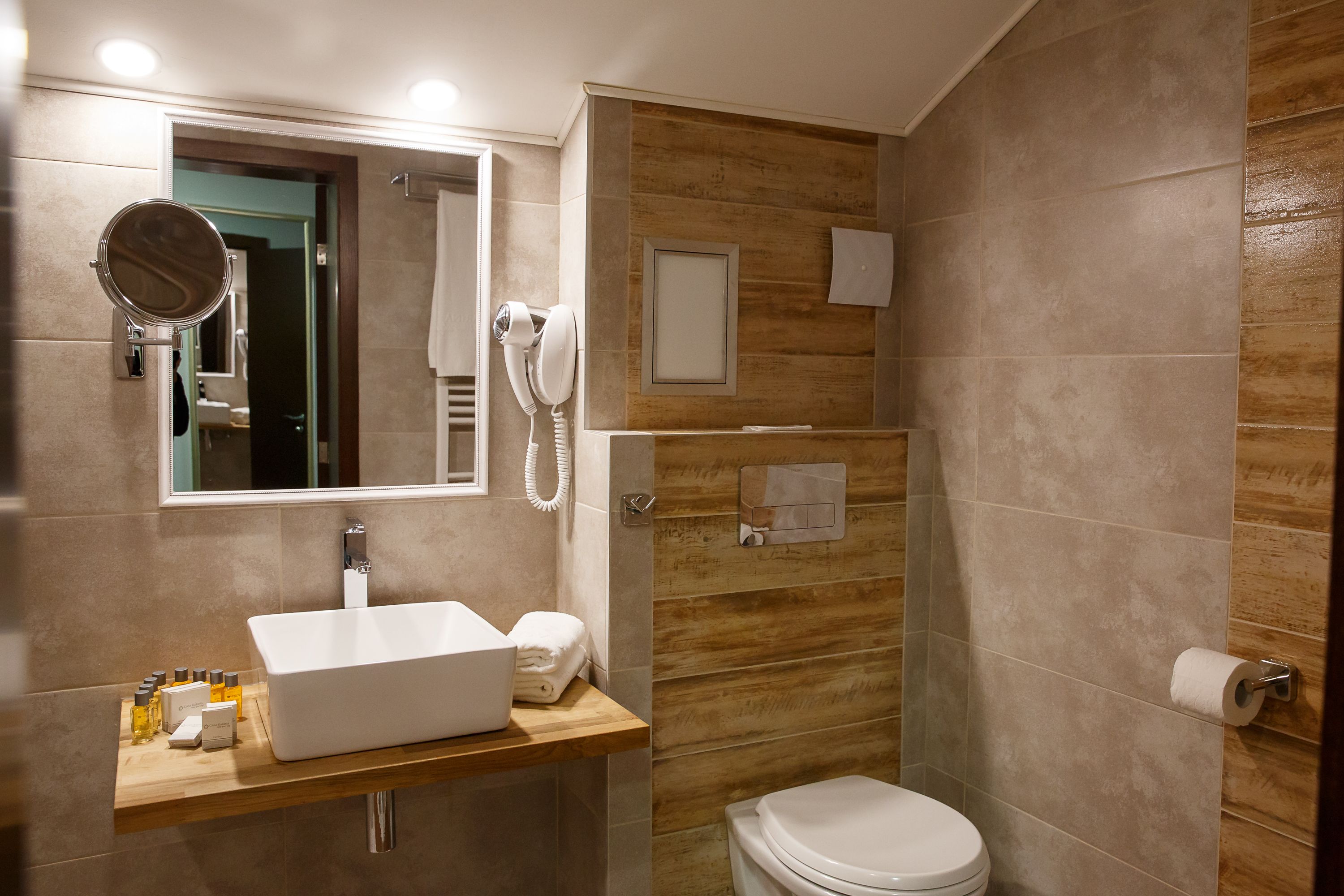 A modern bathroom with a white sink, mirror, and toilet.