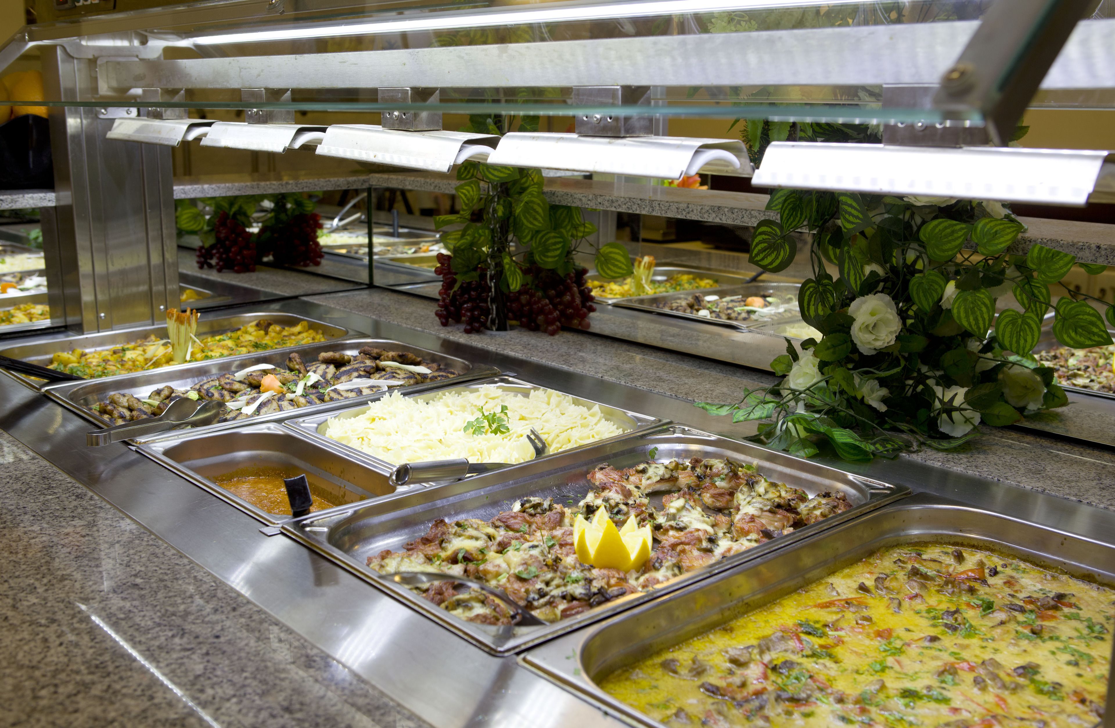 Un bufé con diversas opciones de comida, como ensaladas, carnes y platos de pasta.