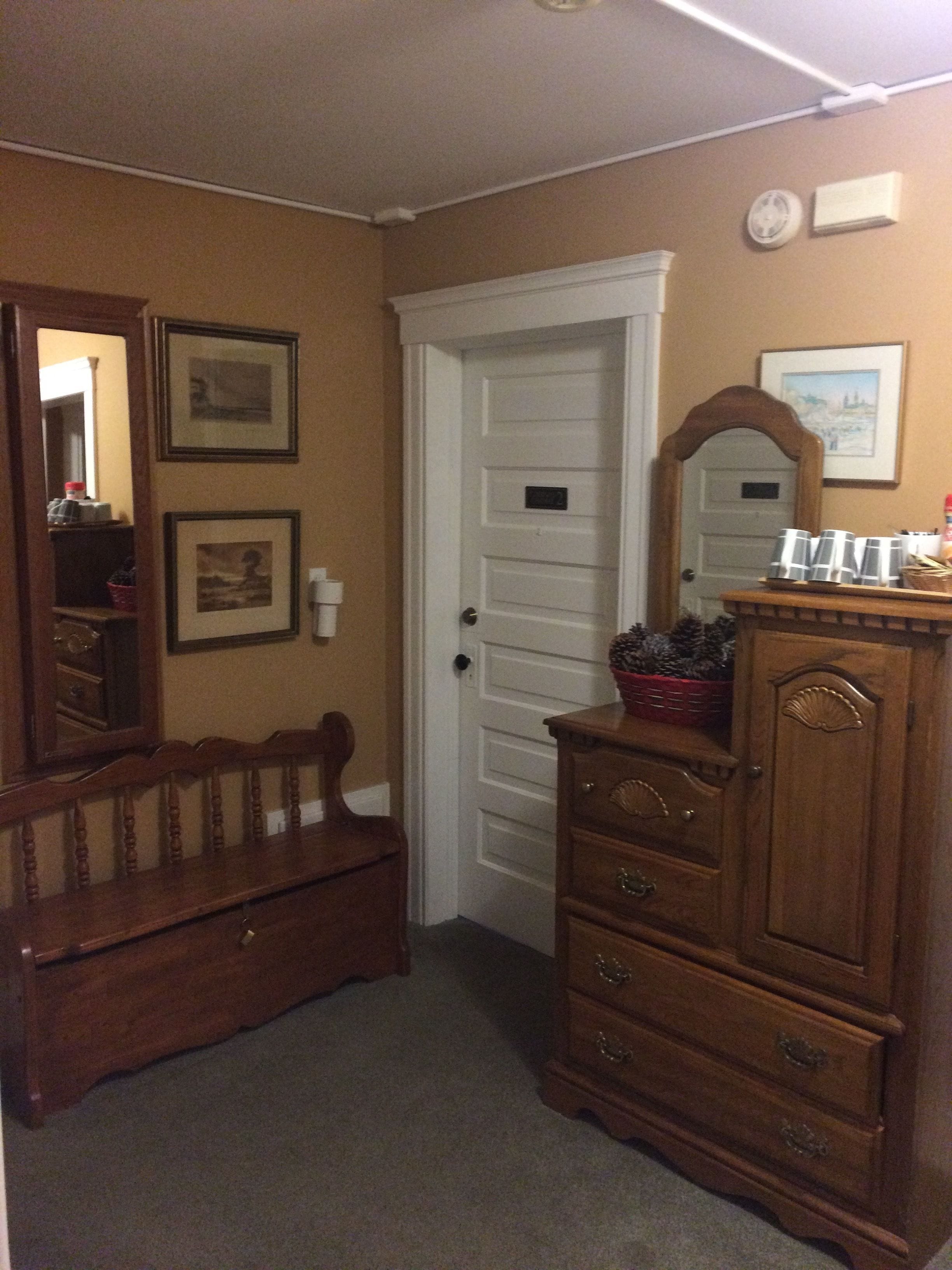 A room with a wooden bench, a dresser, and a door.