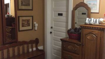 A room with a wooden bench, a dresser, and a door.