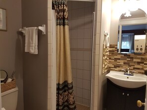 Bathroom features a shower area with a patterned curtain, a sink with a mirror, and mosaic tile walls.