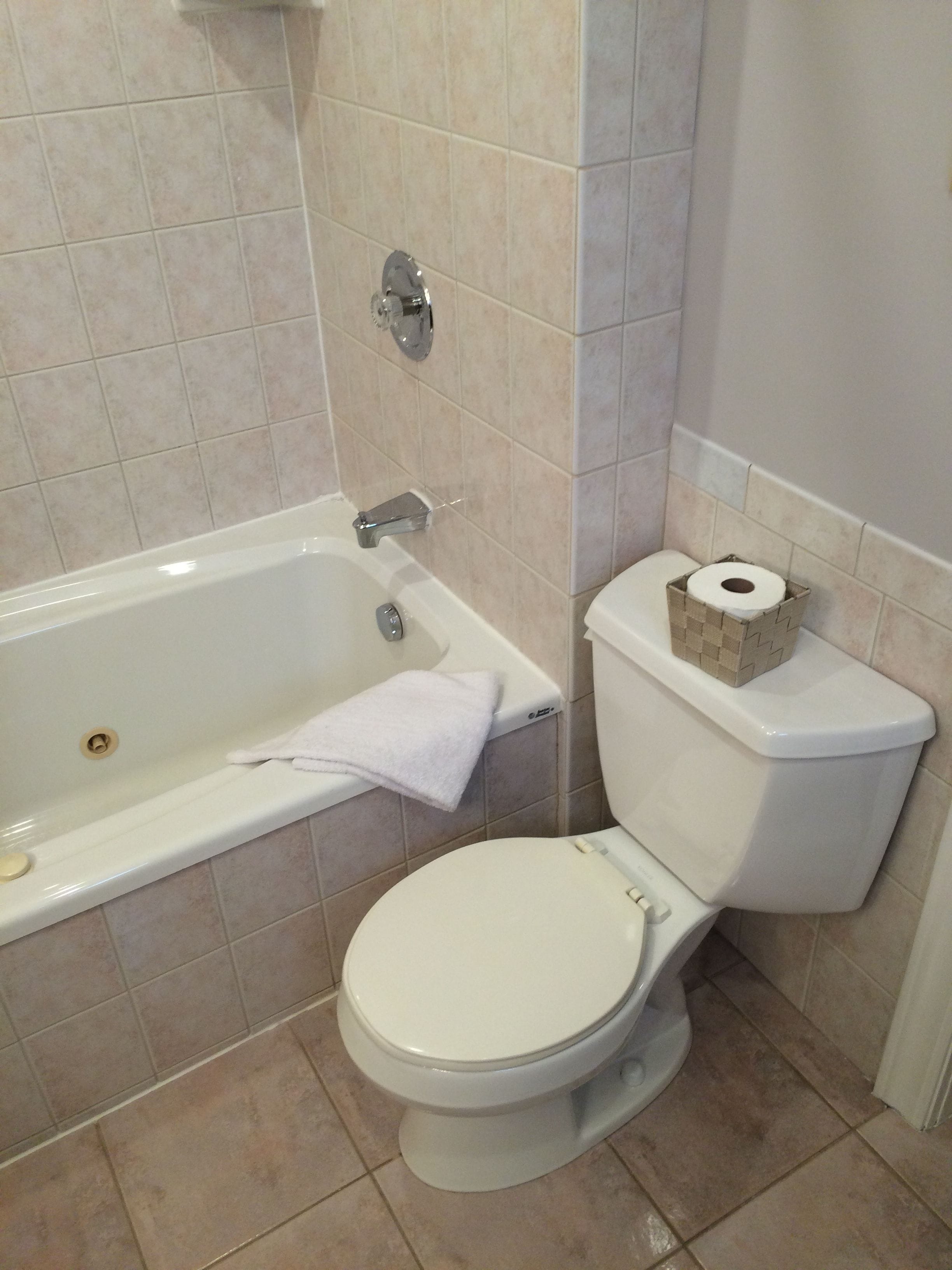 Un baño con una bañera blanca, un inodoro y un perchero para toallas.