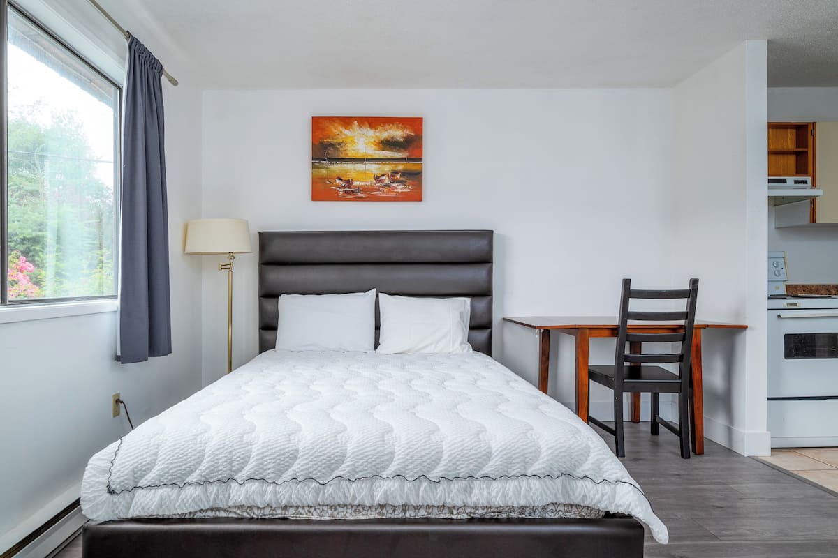 A bedroom with a bed, a desk, and a chair.