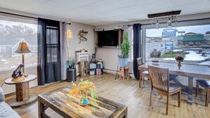 A cozy living room with a wooden coffee table, a television, and a view of a motel sign outside. - Bel Aire Motel Chamberlain Near Missouri River I 90 (Chamberlain)