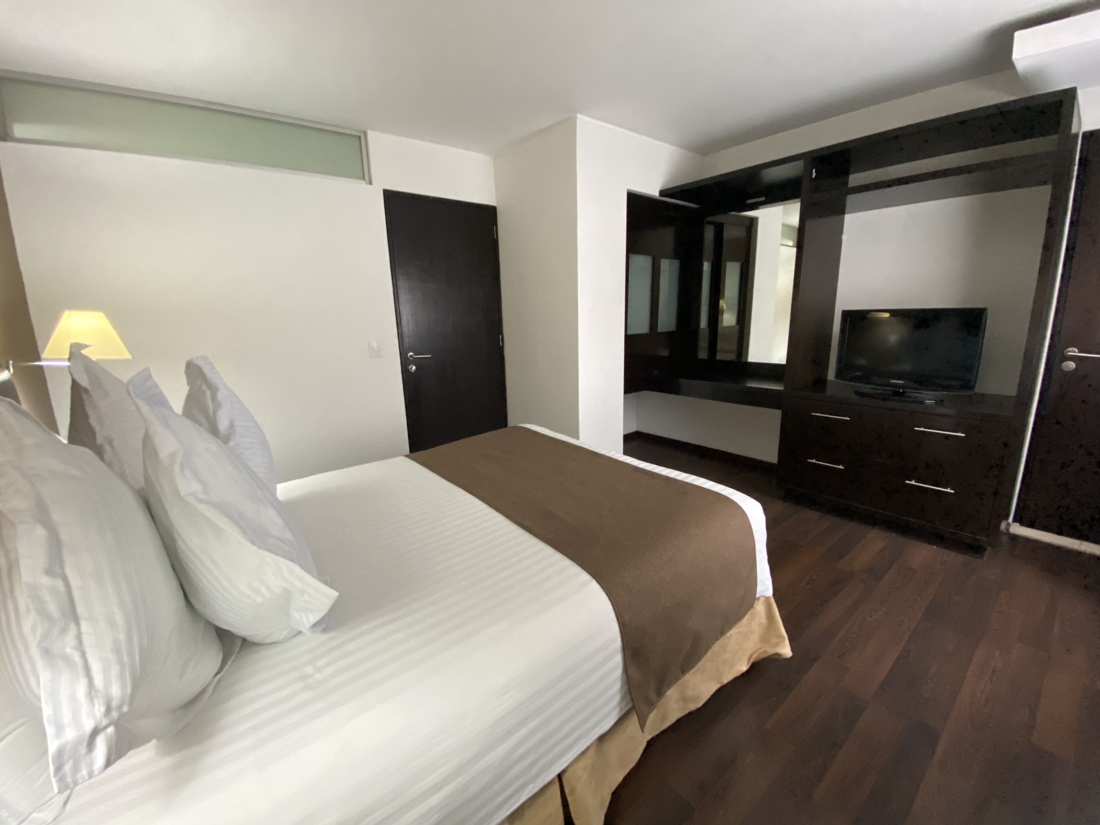 Une chambre d’hôtel avec un lit, une télévision, une armoire et un miroir.