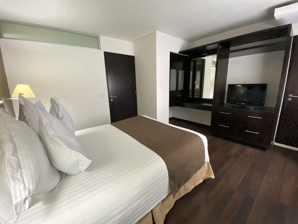 A hotel room with a bed, a TV, a wardrobe, and a mirror.