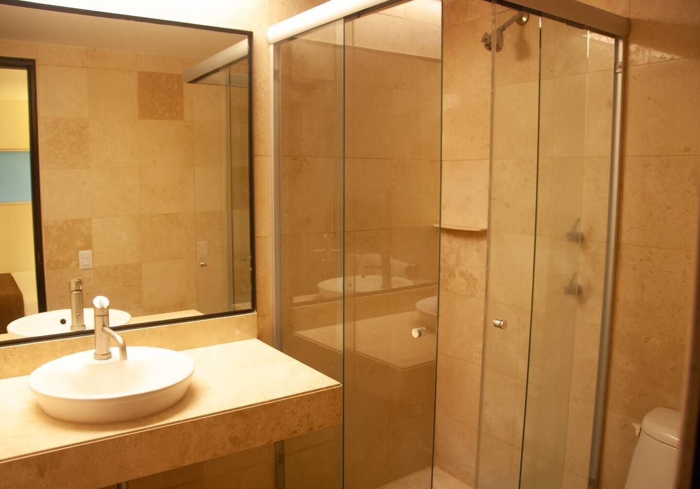 Ein Badezimmer mit einer Duschkabine, einem Waschbecken mit Spiegel und einer Toilette.