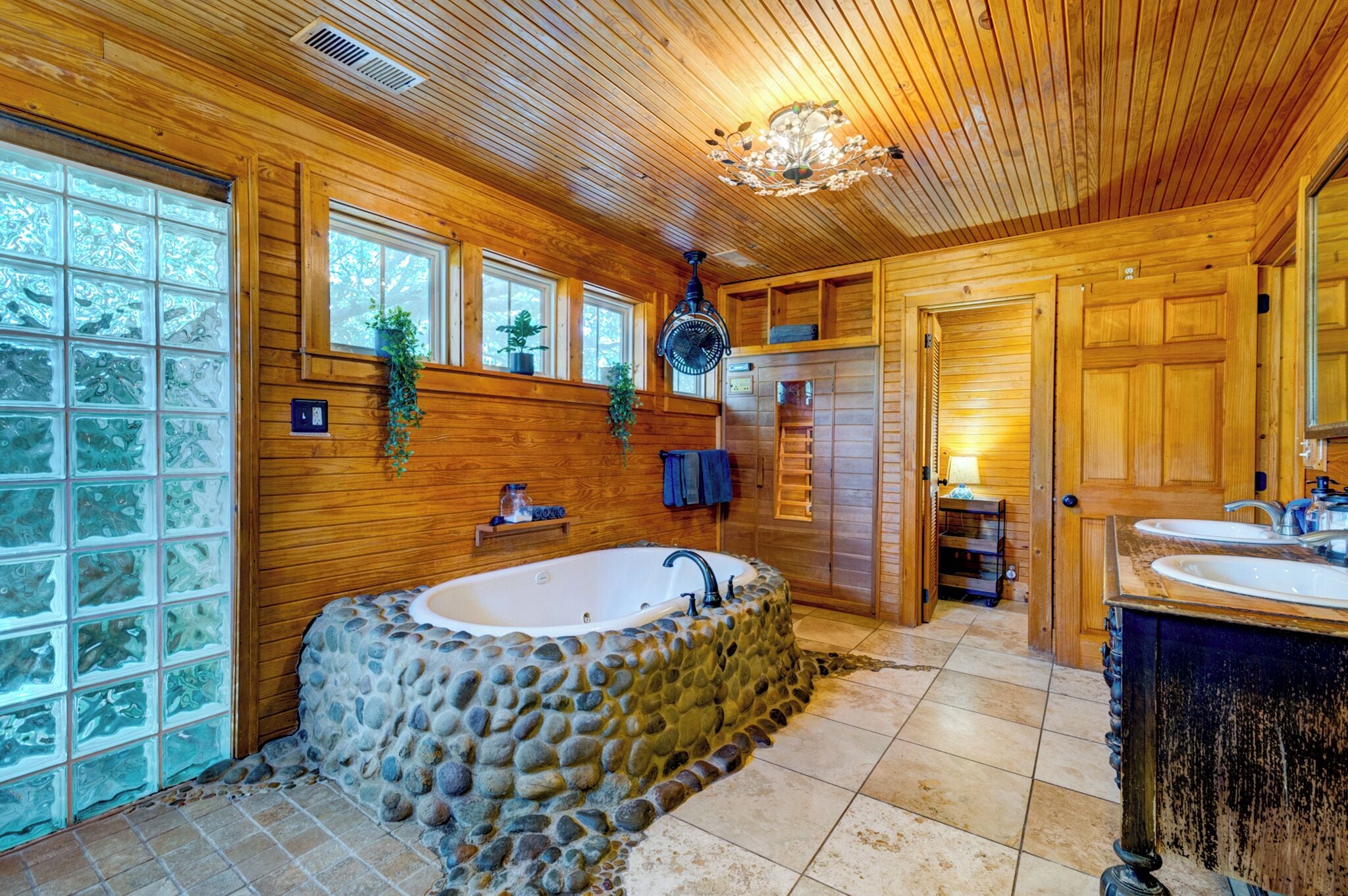 Ein Badezimmer mit einer Steinbadewanne, Holzwänden und einem großen Fenster.